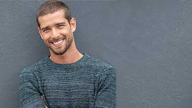 Male standing against gray wall