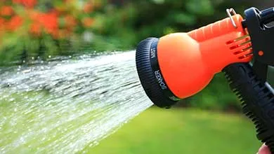 orange garden hose spraying water
